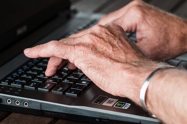 emeryt pracuje na laptopie